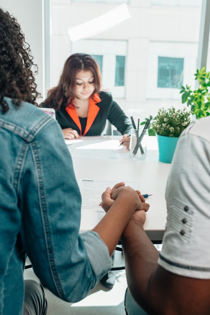 Couple holding hands during an adoption meeting with a social worker in an office setting.